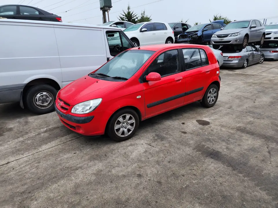 Red hatchback parked beside a white van